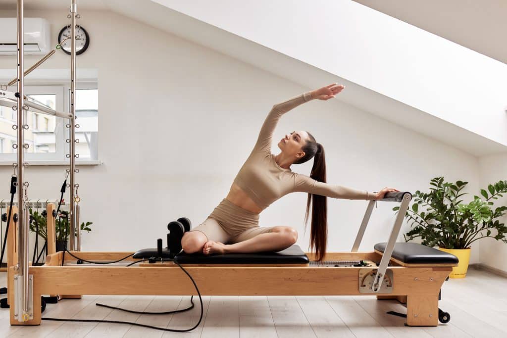Femme pratiquant le Pilates sur un équipement durable et esthétique dans un intérieur épuré